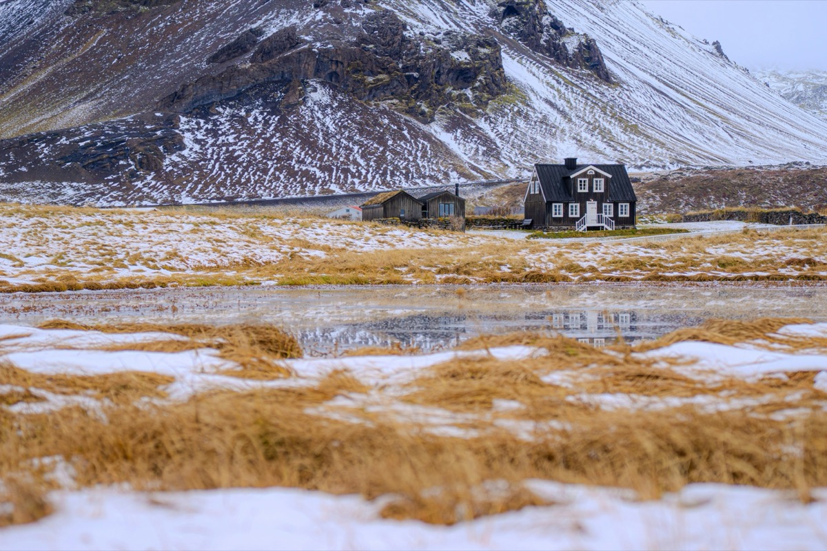 A snow covered mountain with a house in the foreground