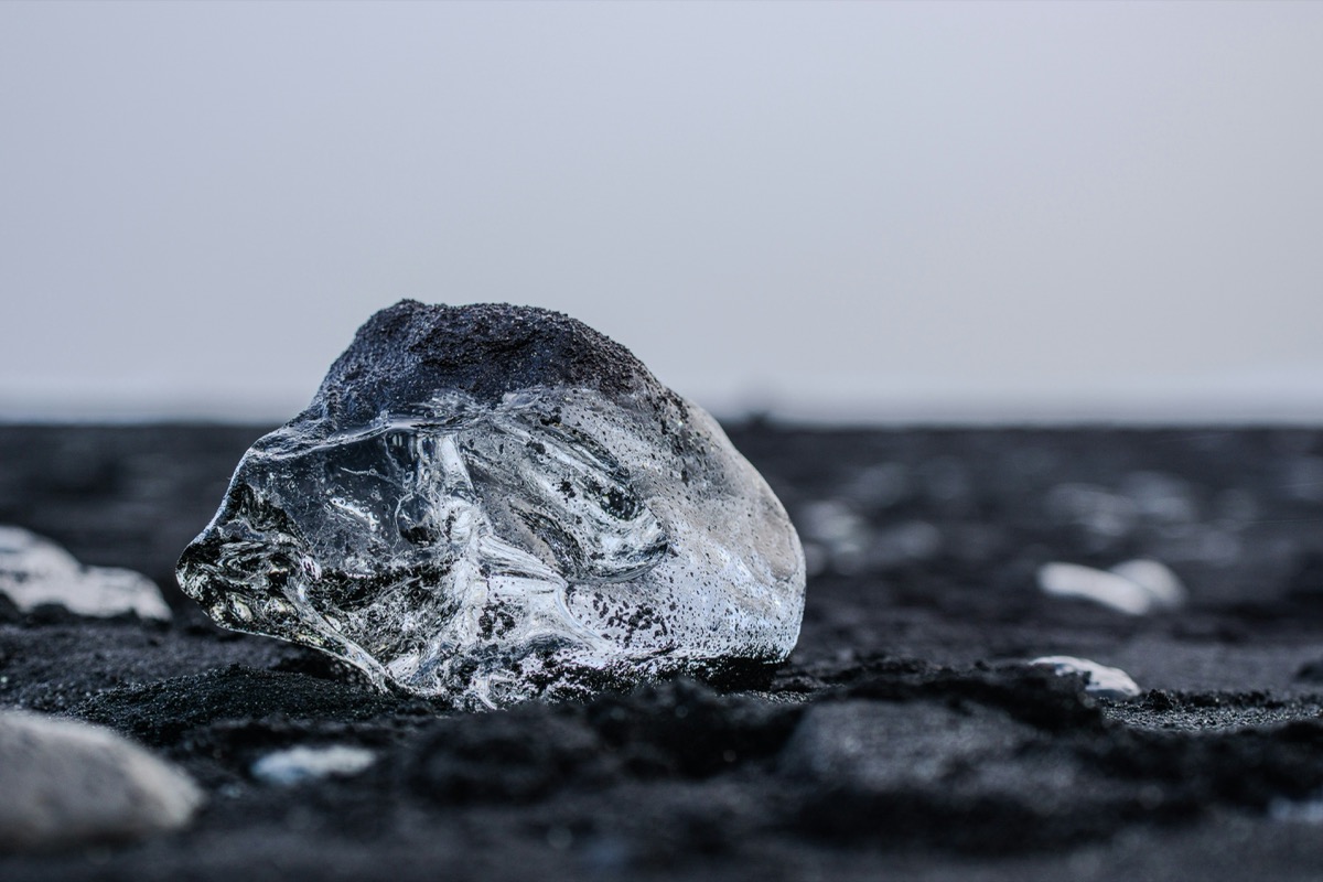 A piece of ice sitting on top of a black ground