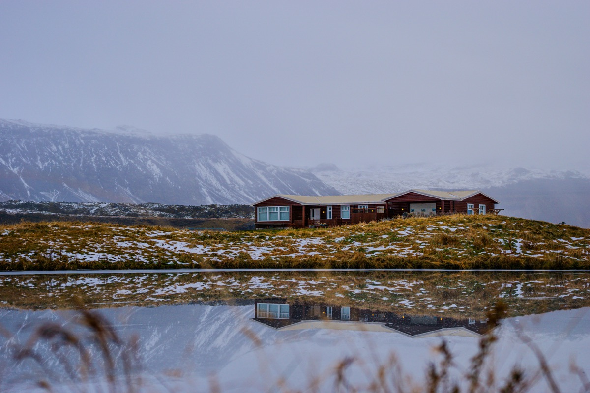 A house sitting on top of a hill next to a lake