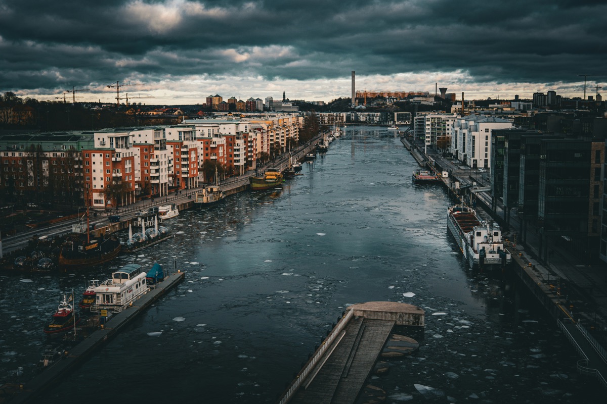 a river running through a city under a cloudy sky