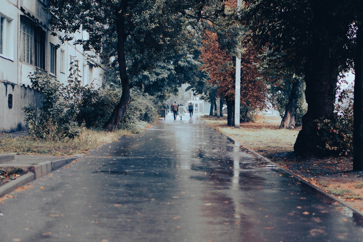 a wet street with people walking down it